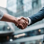 Meeting success. Two business persons shaking hands standing outside